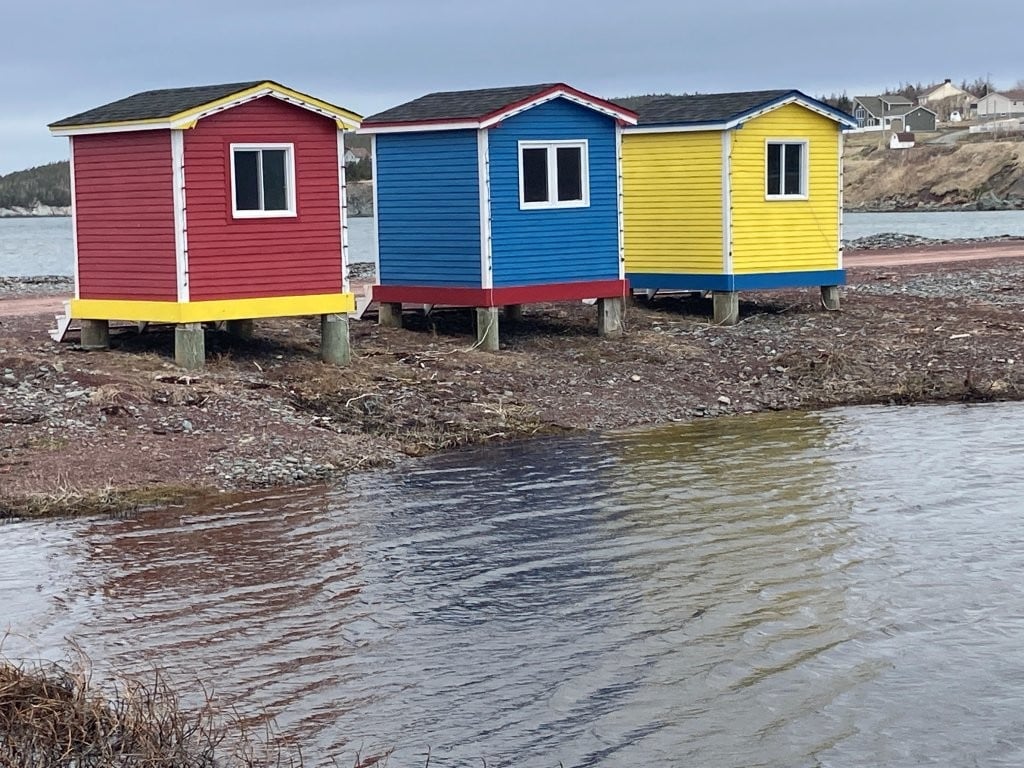 Three brightly coloured fishing shacks