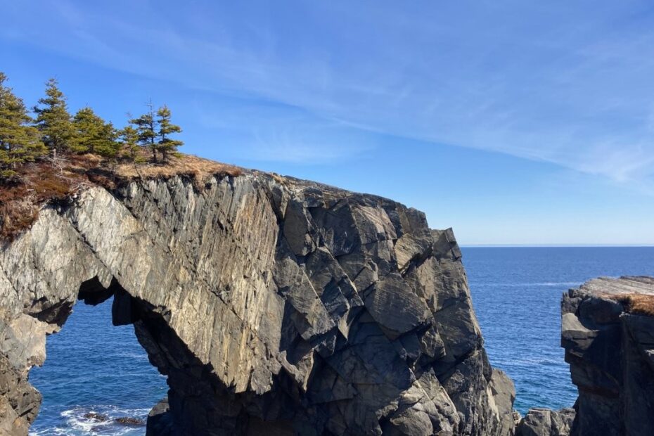 Woman on a rock looking at a large rock arch