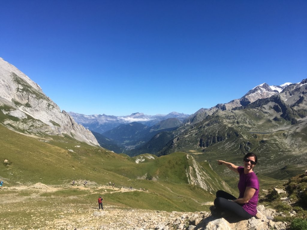Woman pointing down a large green mountain valley
