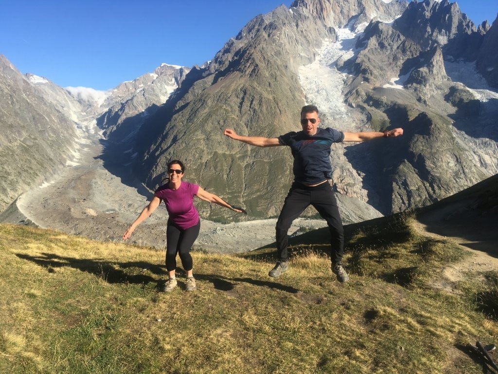 Couple trying to jump together in front of the mountains