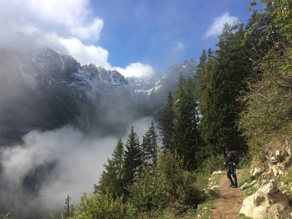 Hiker on trail next to valley and mountains