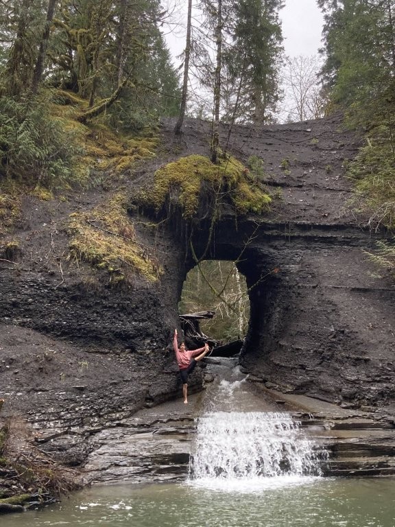 Woman posing in front of the Hole-in-the-Wall waterfall on Vancouver Island
