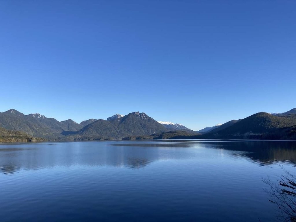 Calm reflective bay with green hills behind