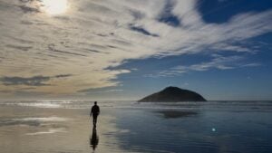 Woman walking on a long flat beach with the tide out