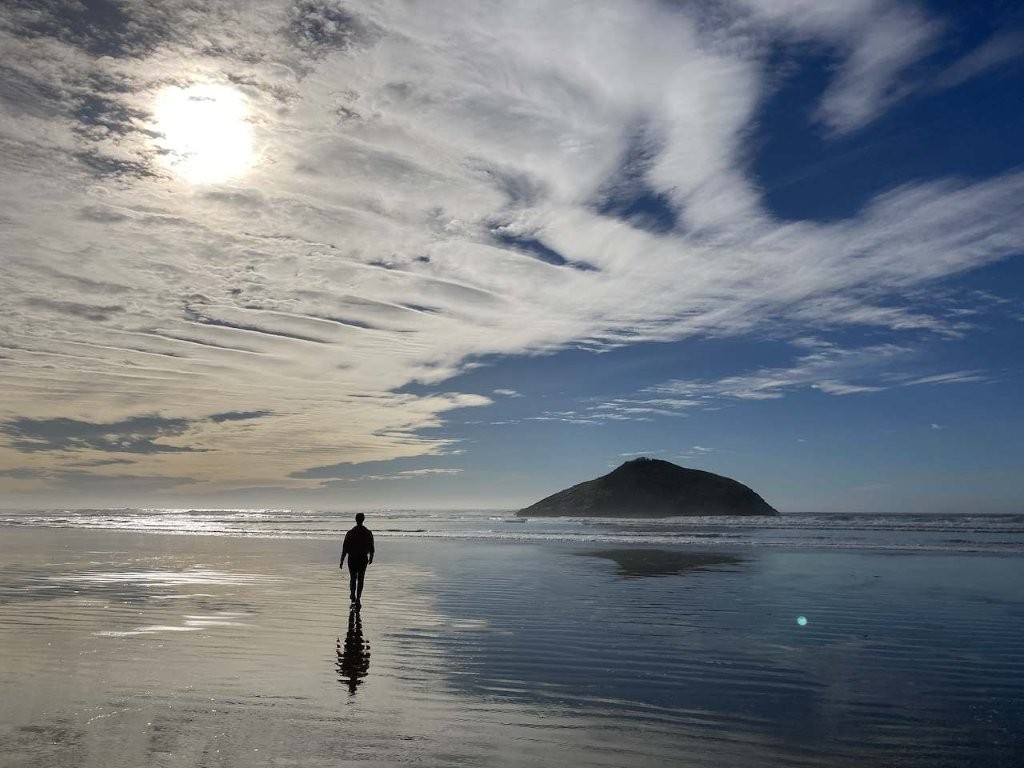 Woman walking on a long flat beach at low tide