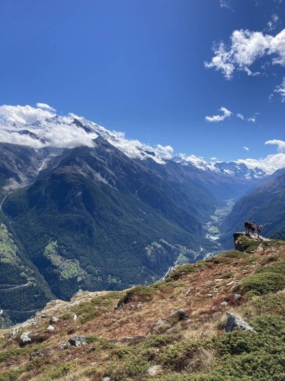 Hikers on rock overlooking a mountain valley