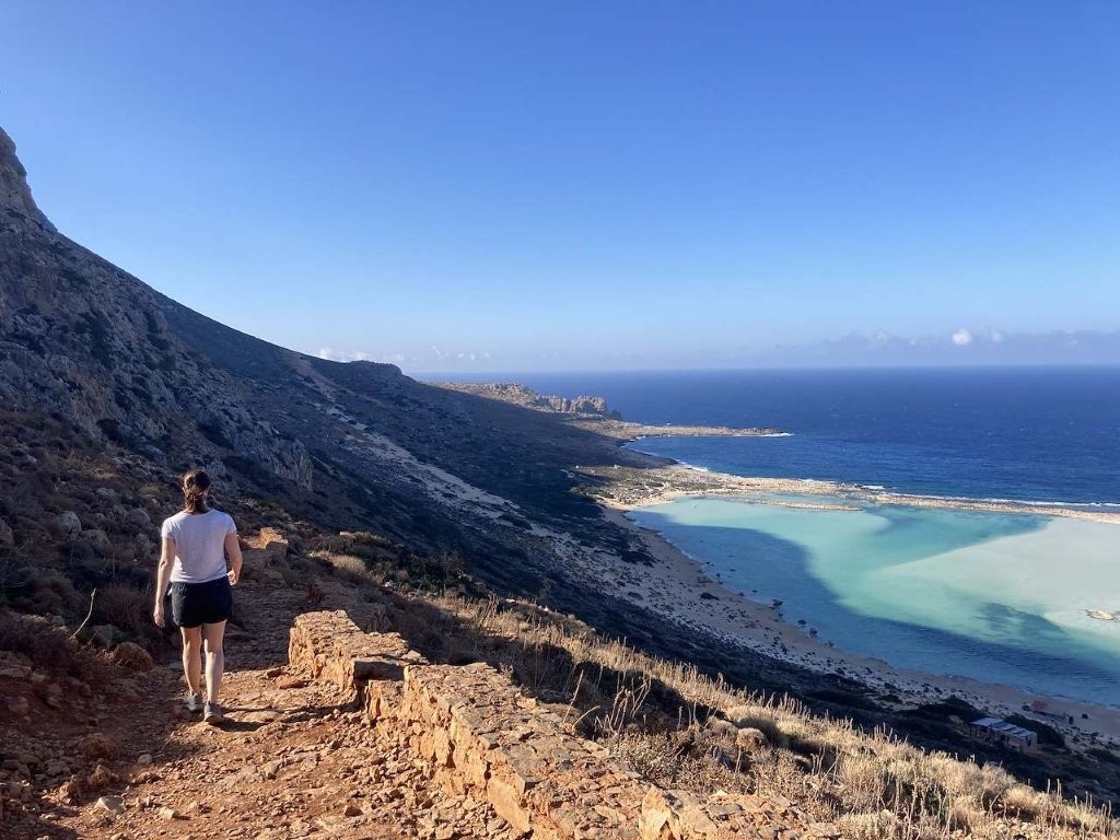 Woman walking down stone path toward Balos Beach