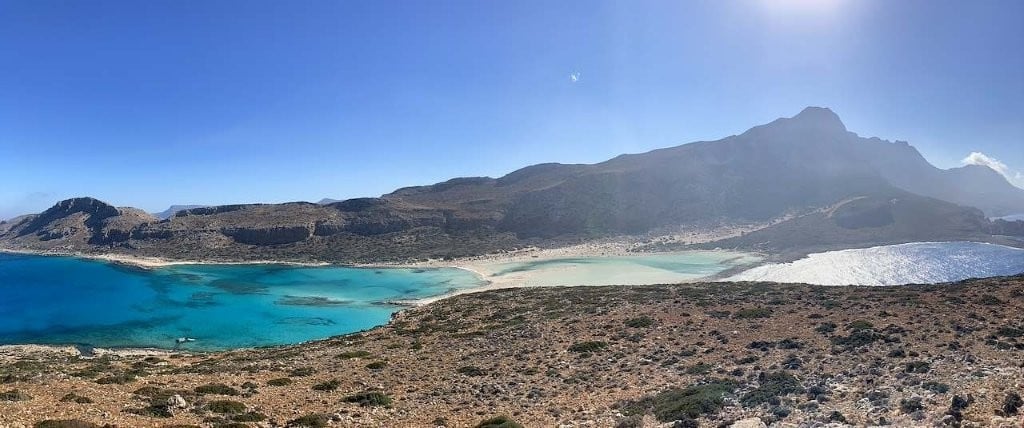 Two blue bays separated by a sandbar and backed my mountains