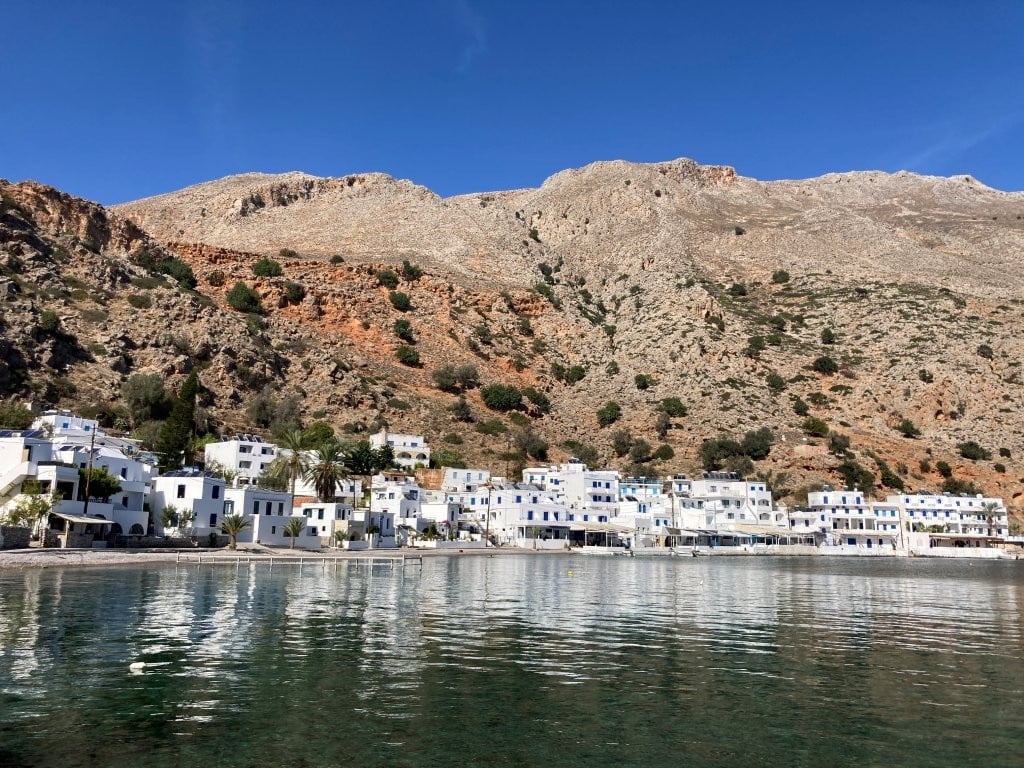 White village on shore of bay with brown hills behind