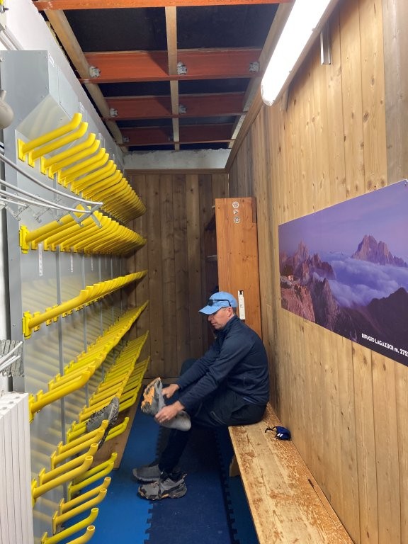 Man putting on hiking shoes in Rifugio Lagazuoi boot room