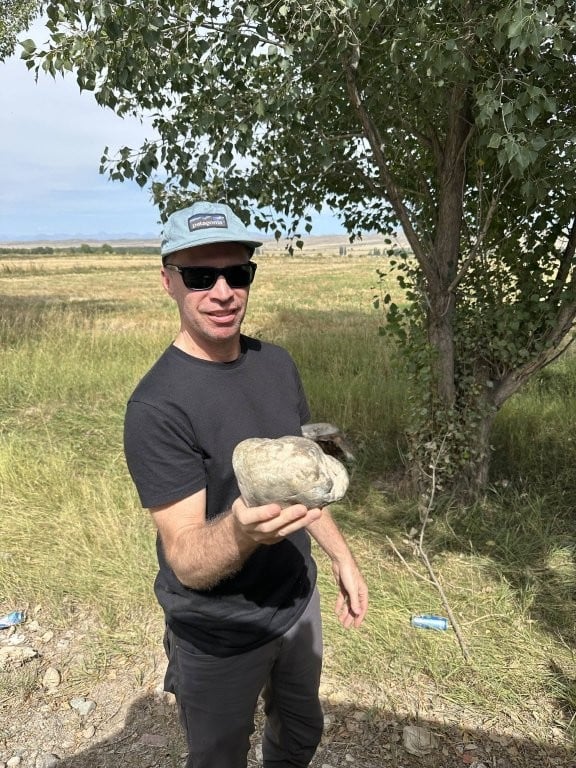 Man holding large rock that had jammed between tires