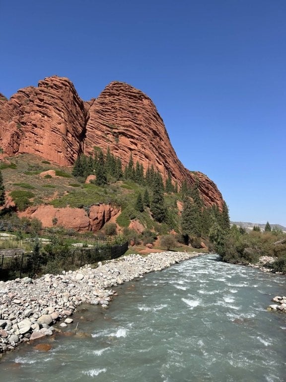 Rushing stream with large red rock formations behind
