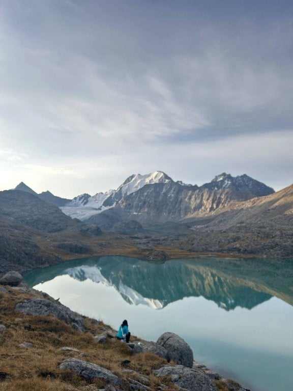 Woman on rock overlooking calm alpine lake