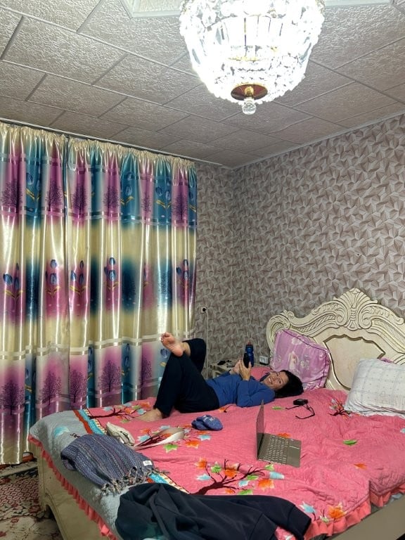 Woman on pink bed with bright curtains and wallpaper