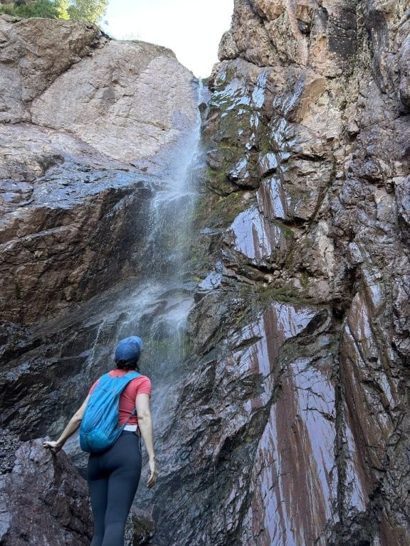 Woman looking up at a high waterfall