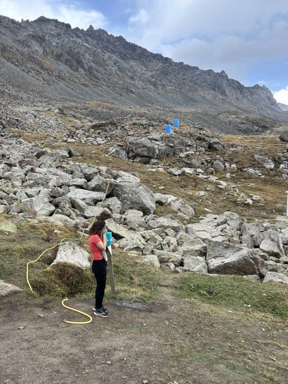 Woman washing her face from a mountain hose