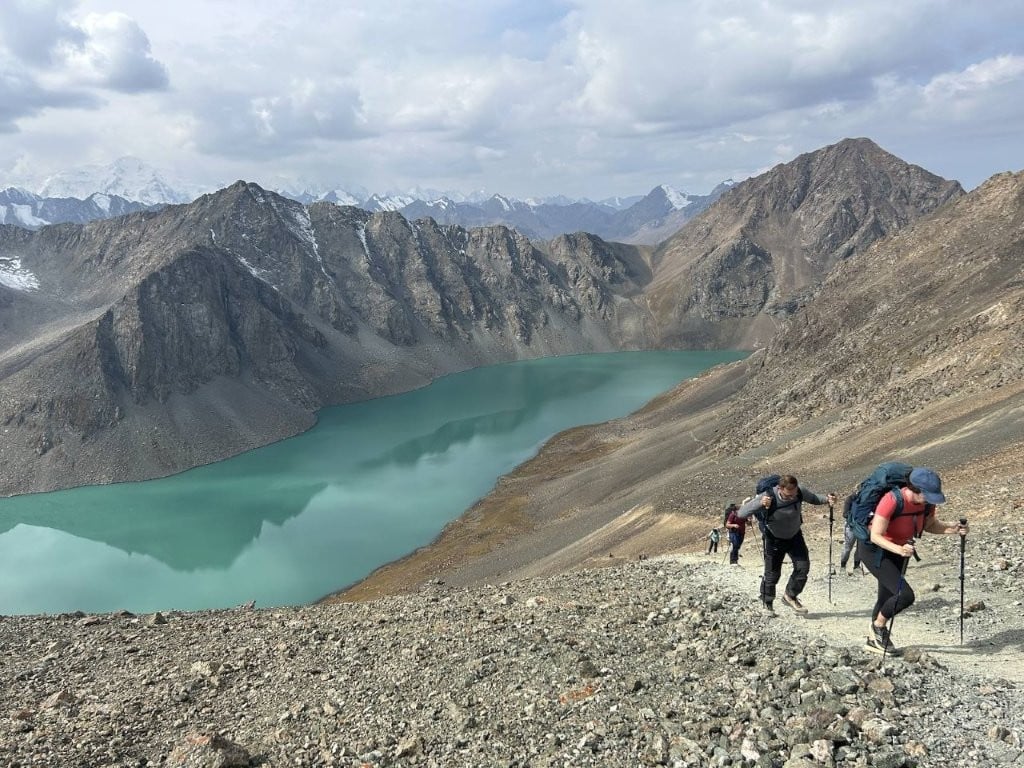Hikers coming up steep slope from lake on Ala Kul trek