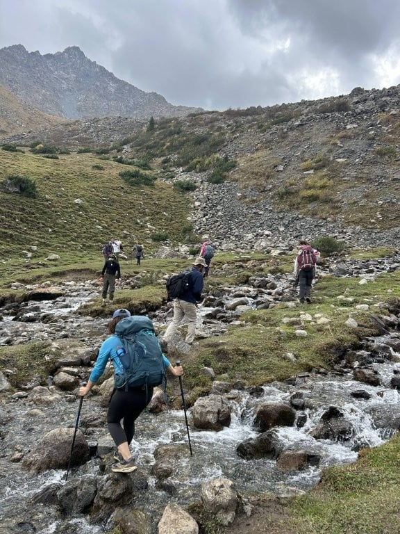Hikers crossing rocky stream
