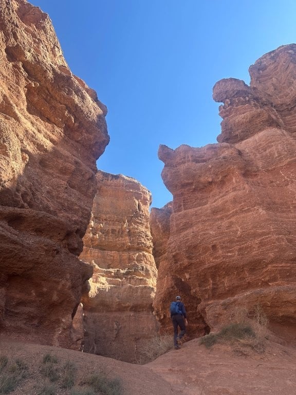 Man hiking up between rocks in Charyn Canyon