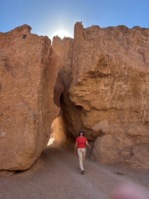 Woman walking out from under a narrow rock arch