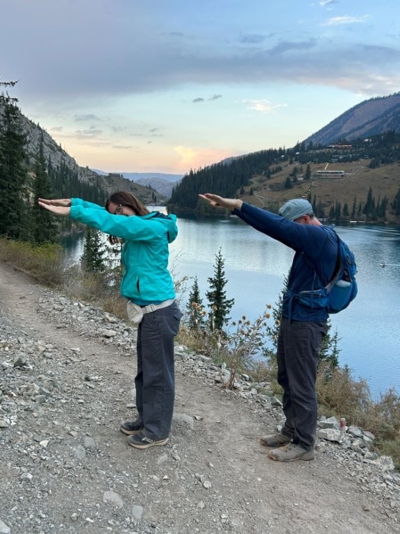 Two people trying to look like the number 7 in front of a lake