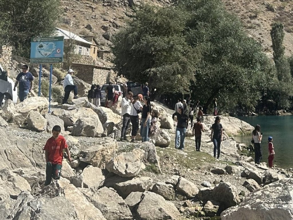 People mingling on the edge of a lake in Tajikistan