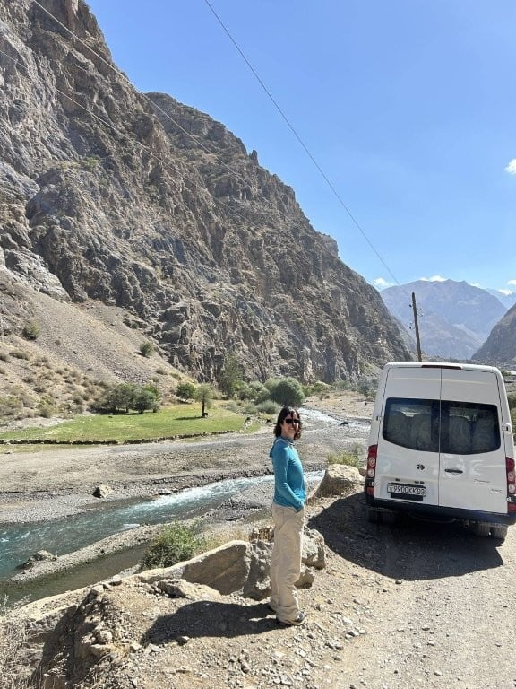 Woman standing next to a tourist van on the Seven Lakes of the Fann Mountains day trip